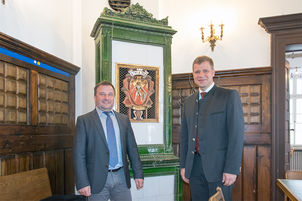 Bezirkstagspräsident Dr. Olaf Heinrich und Zwiesels Bürgermeister Karl-Heinz Eppinger vor dem alten Kaminofen im Sitzungssaal des Rathauses.