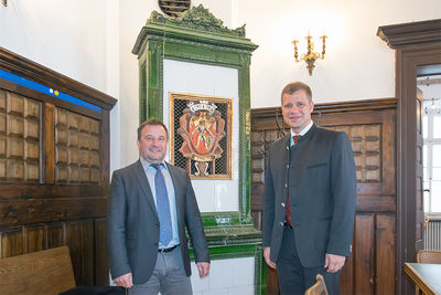 Bezirkstagspräsident Dr. Olaf Heinrich und Zwiesels Bürgermeister Karl-Heinz Eppinger vor dem alten Kaminofen im Sitzungssaal des Rathauses.