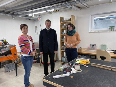 Veronika Zotter (l.) und Henriette Olbertz-Weinfurter (r.) führten Bezirkstagspräsident Dr. Olaf Heinrich durch die Gründerwerkstatt Glas in Zwiesel. 